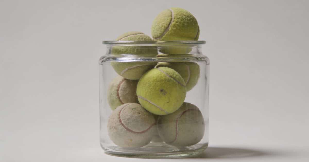 Bac transparent rempli de vieilles balles de tennis