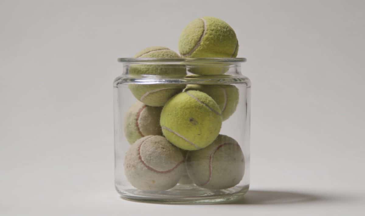 Bac transparent rempli de vieilles balles de tennis