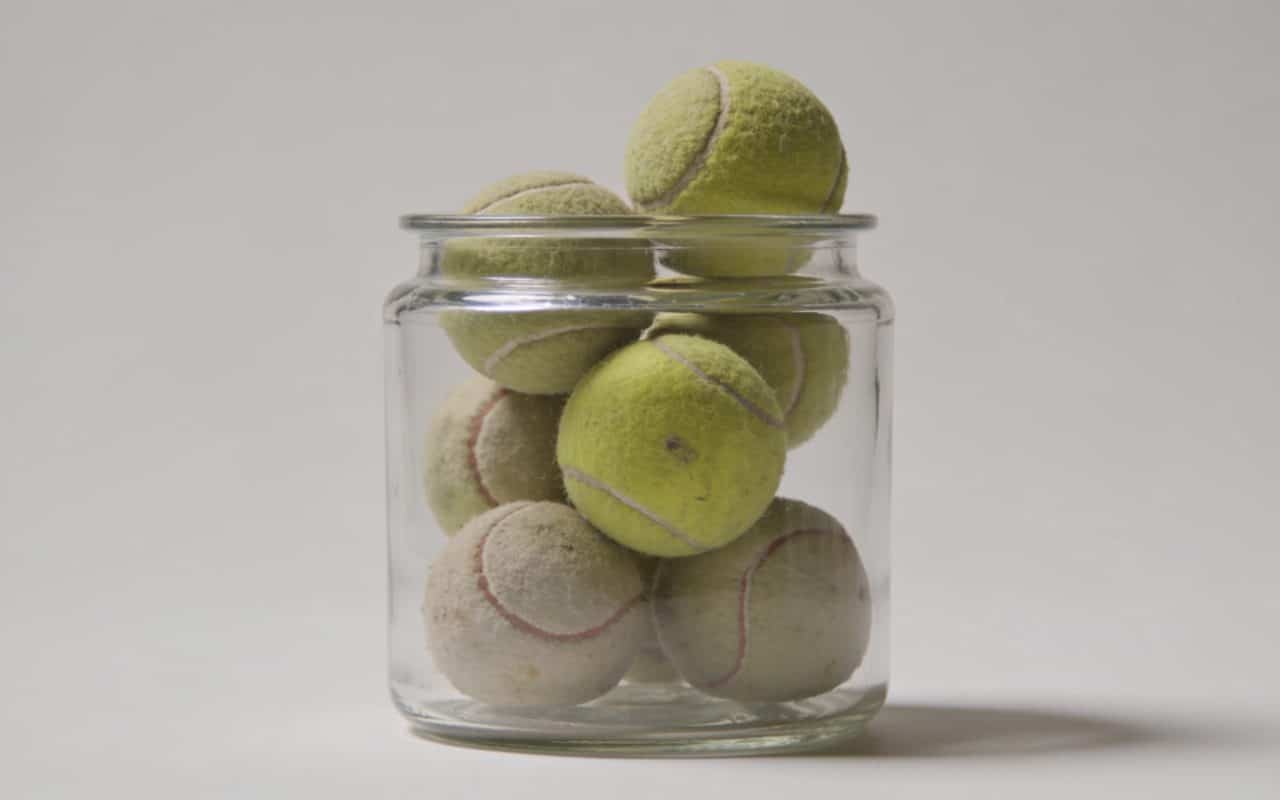 Bac transparent rempli de vieilles balles de tennis