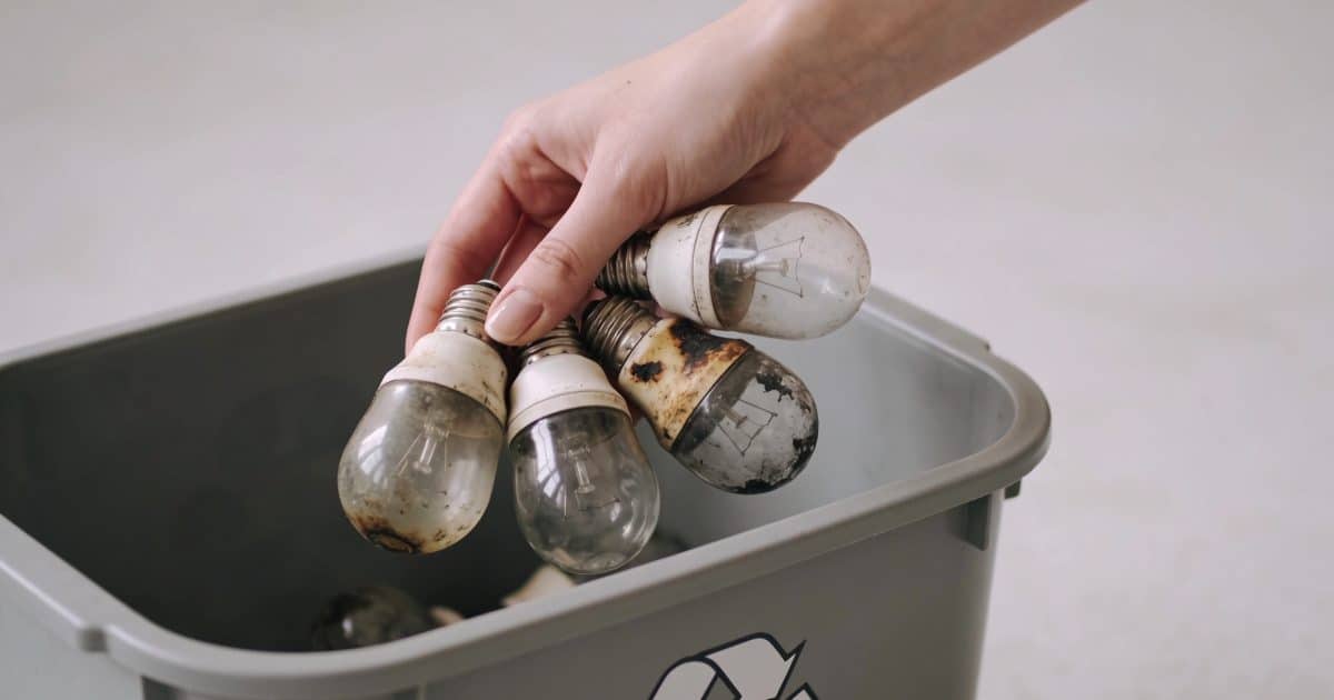 Femme depose vieilles ampoules grillees dans conteneur recyclage