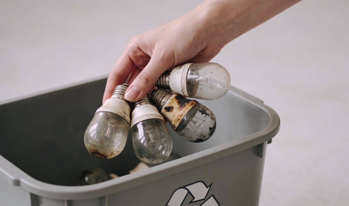 Femme depose vieilles ampoules grillees dans conteneur recyclage