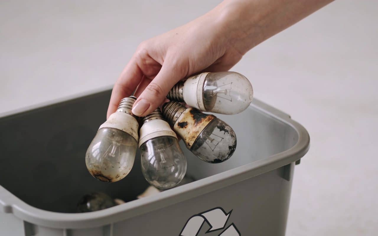 Femme depose vieilles ampoules grillees dans conteneur recyclage