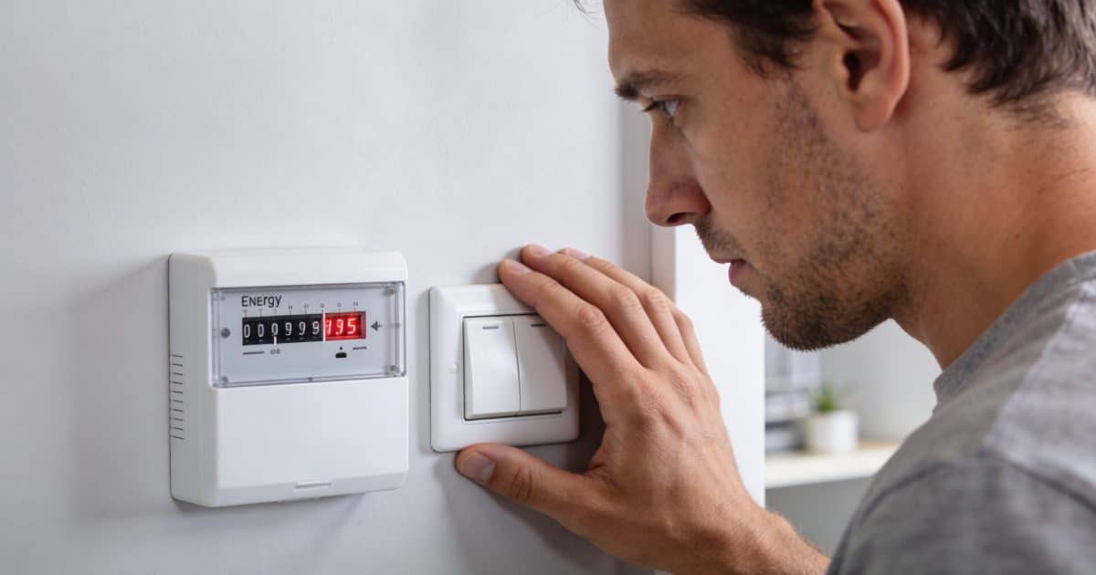 Homme regarde compteur energie augmente pese sur interrupteur