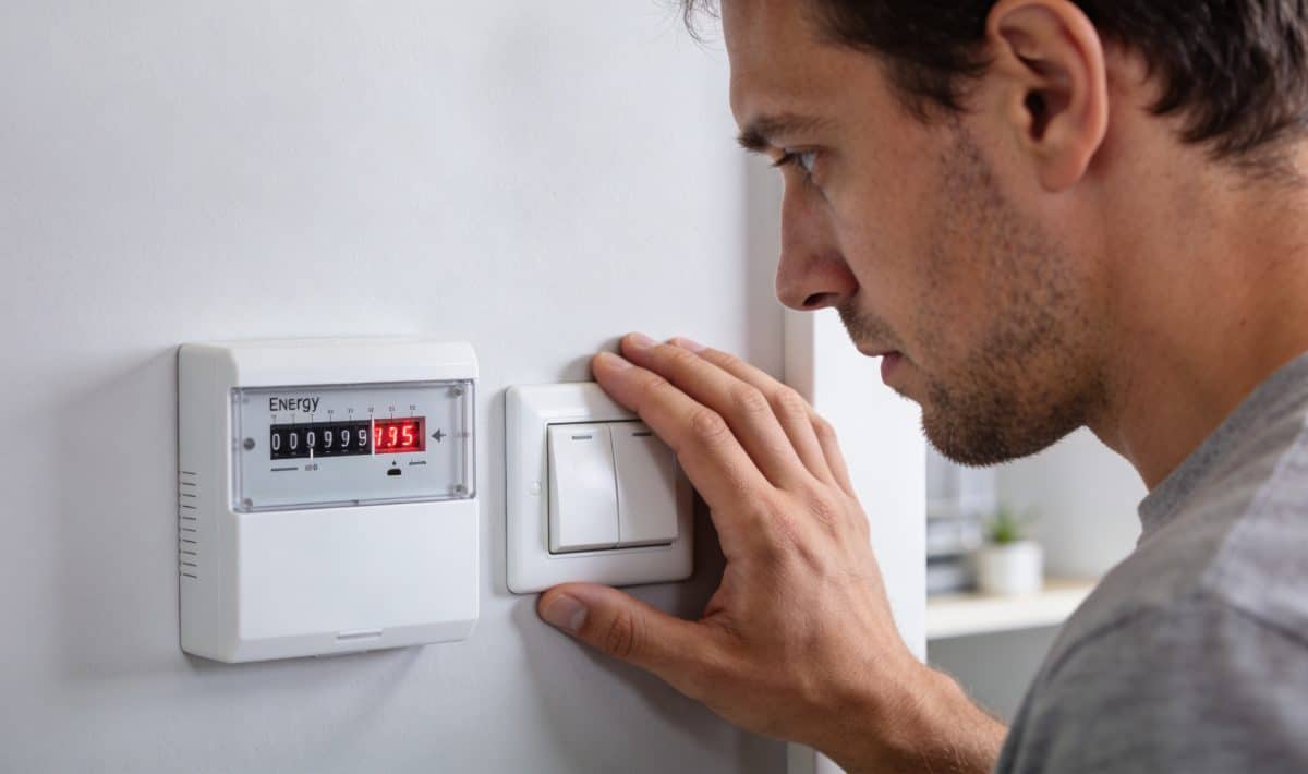 Homme regarde compteur energie augmente pese sur interrupteur