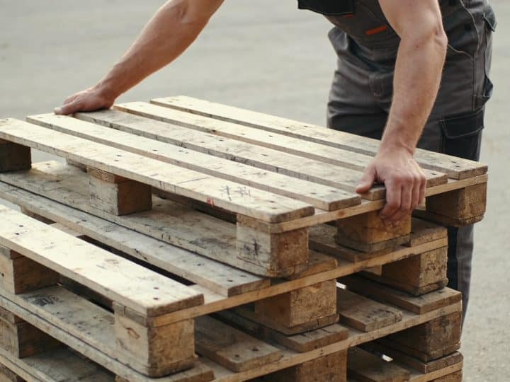 Ouvrier empilant des palettes en bois usees dehors