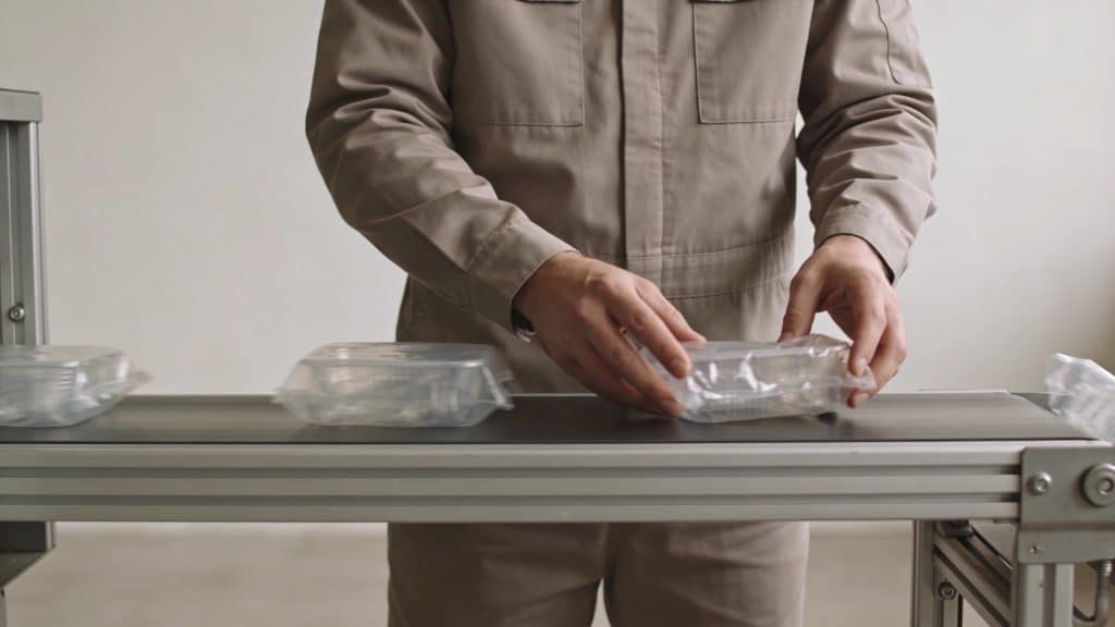 Ouvrier triant des emballages plastiques sur tapis roulant