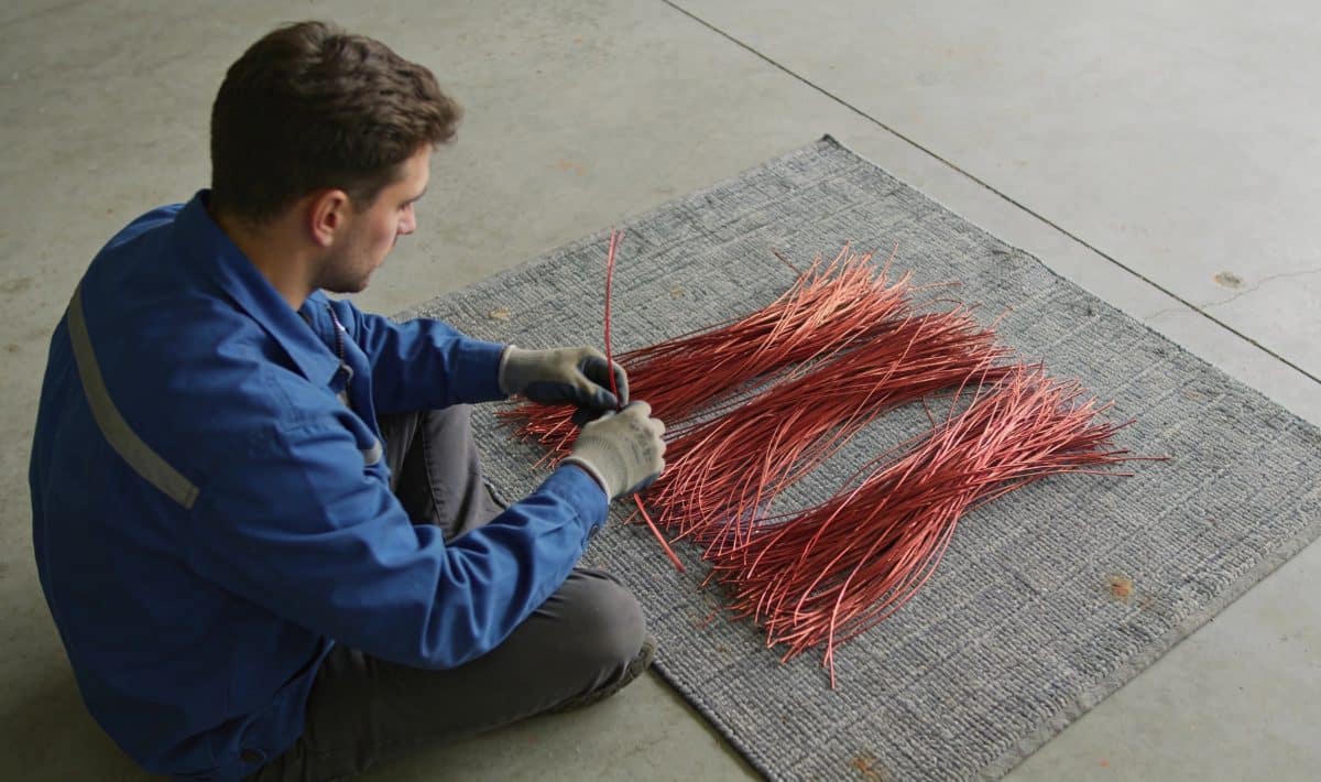 Ouvrier trie fils de cuivre rouges sur tapis