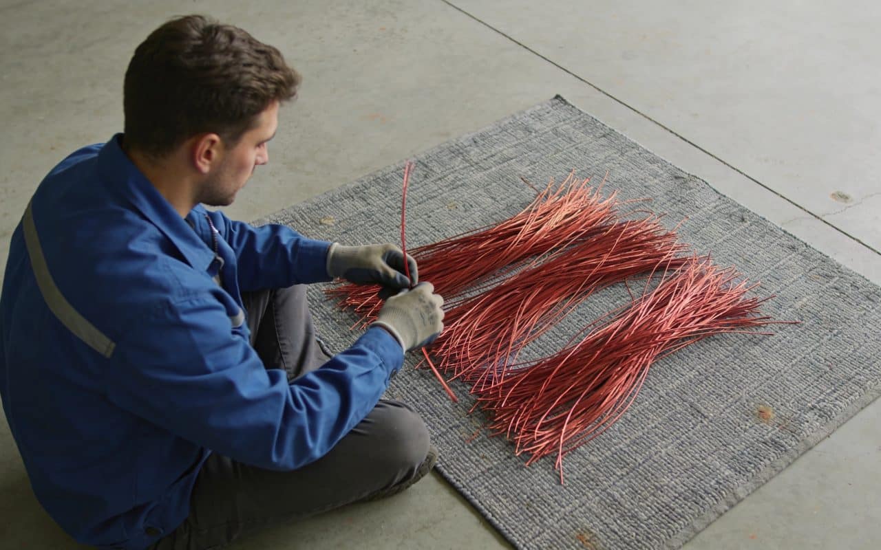 Ouvrier trie fils de cuivre rouges sur tapis