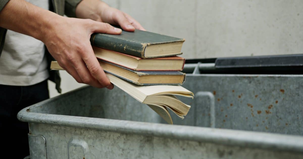 Personne deposant des livres uses dans une benne
