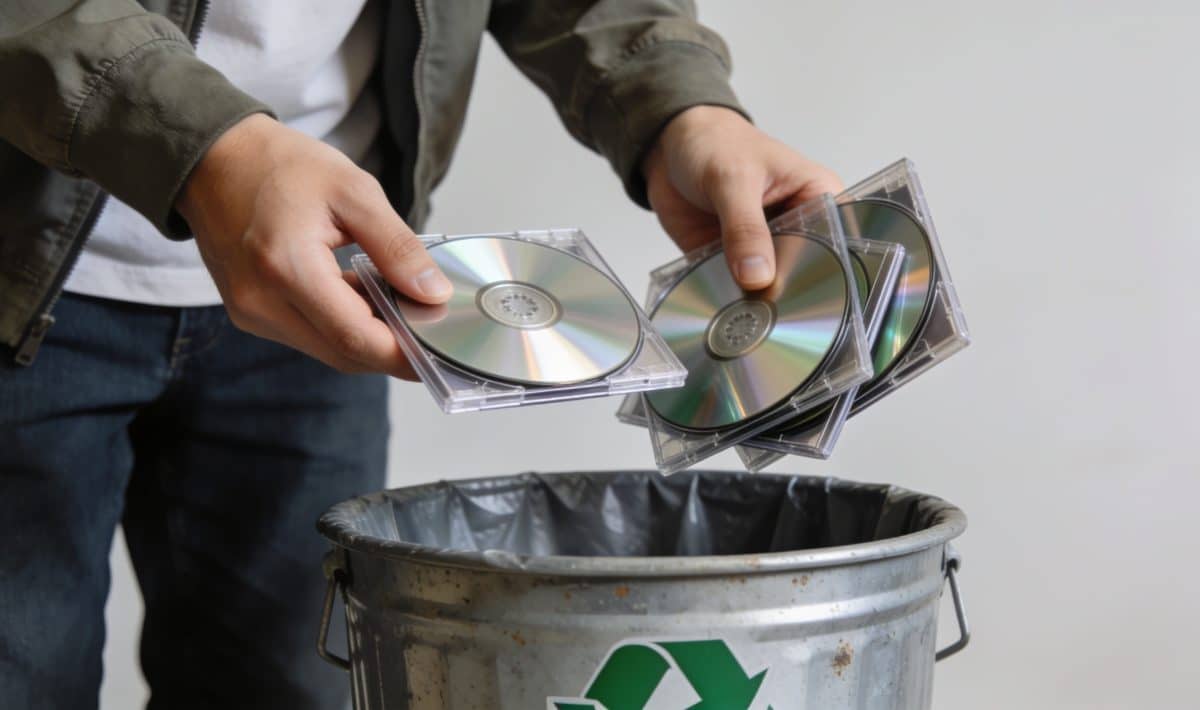 Personne deposant des CD dans une benne de recyclage