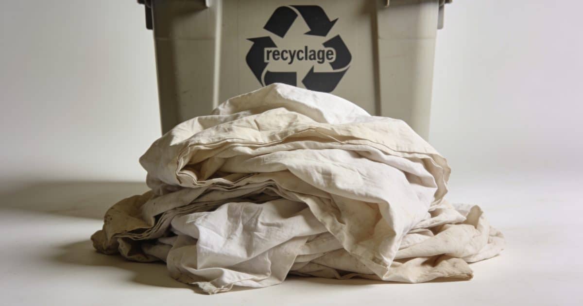 Tas de vieux draps froisses devant conteneur recyclage