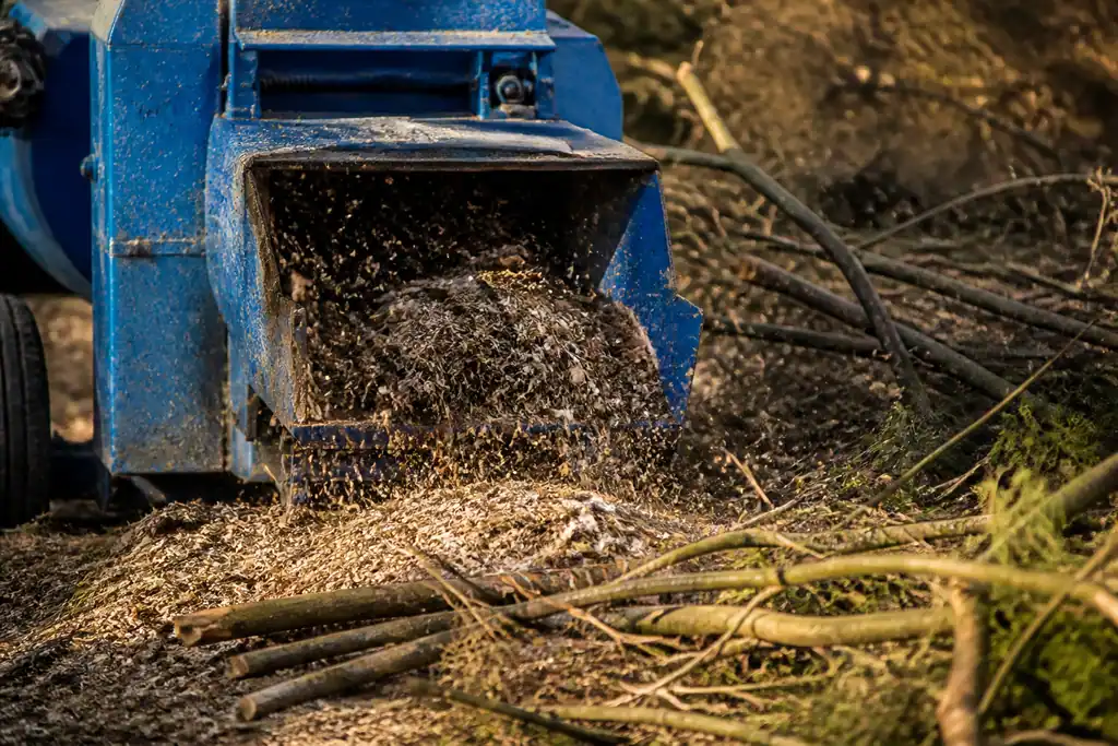 Machine bleue broyant des branches au sol