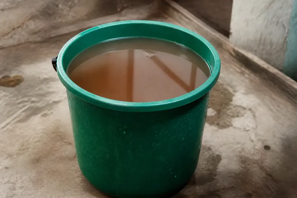 Seau en plastique vert rempli de liquide brun